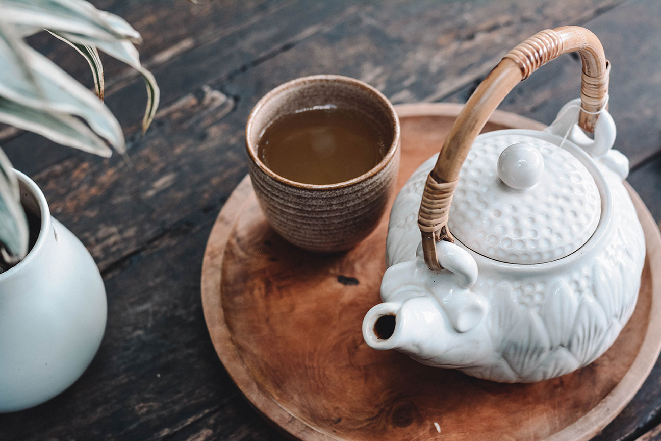 white teapot and wooden teacup with green tea